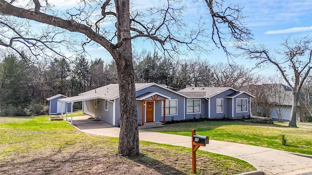 view of front facade featuring a carport, a storage shed, and a front lawn