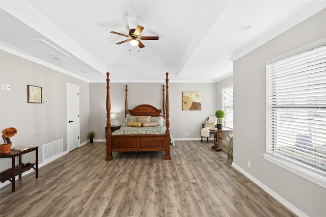 bedroom with a raised ceiling, crown molding, hardwood / wood-style floors, and ceiling fan