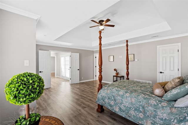 bedroom with crown molding, hardwood / wood-style flooring, a raised ceiling, and ceiling fan