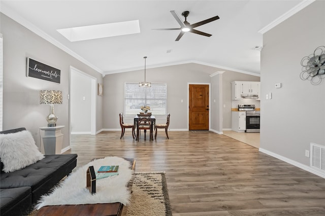 living room with hardwood / wood-style flooring, ceiling fan, vaulted ceiling with skylight, and ornamental molding