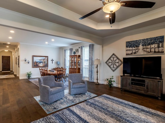 living room featuring a raised ceiling, ornamental molding, dark hardwood / wood-style floors, and ceiling fan