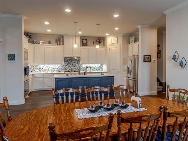 dining room featuring crown molding, sink, and dark wood-type flooring