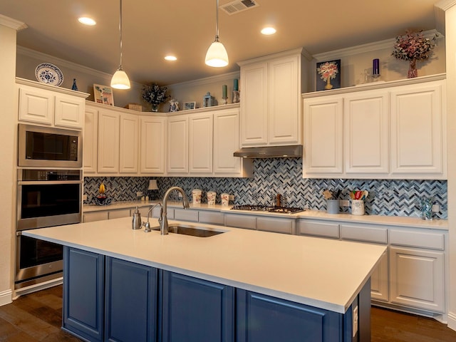 kitchen featuring white cabinetry, sink, hanging light fixtures, stainless steel appliances, and a center island with sink