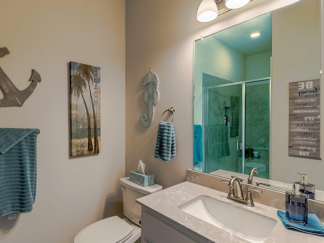 bathroom with vanity, toilet, and a shower with door