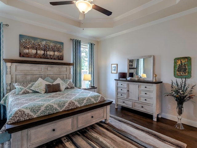 bedroom featuring dark wood-type flooring, ornamental molding, a raised ceiling, and ceiling fan