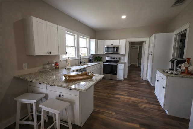 kitchen featuring sink, stainless steel appliances, a kitchen breakfast bar, kitchen peninsula, and white cabinets