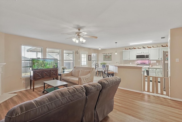 living room with ceiling fan, light wood-type flooring, and sink