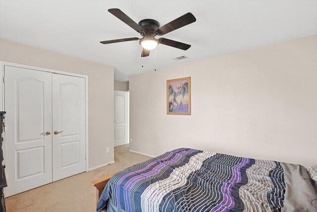 bedroom with ceiling fan, light colored carpet, and a closet