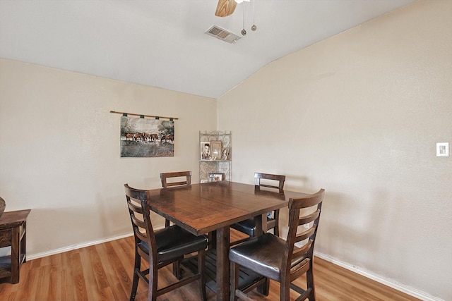 dining room with hardwood / wood-style floors, ceiling fan, and lofted ceiling