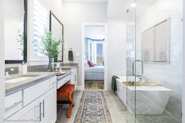 bathroom with independent shower and bath, vanity, plenty of natural light, and tile walls