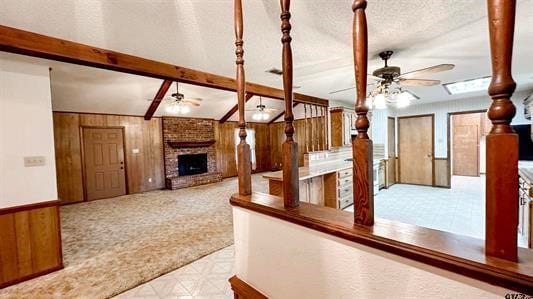 hall with a skylight, beamed ceiling, wood walls, a textured ceiling, and light carpet