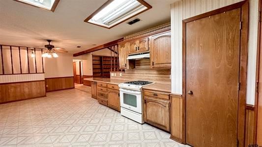 kitchen with wood walls, ceiling fan, and white stove