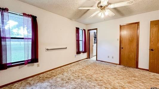 unfurnished bedroom featuring ceiling fan, carpet floors, a textured ceiling, and multiple windows