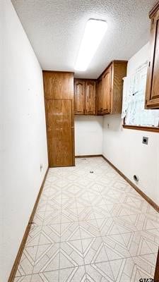 laundry room featuring cabinets, a textured ceiling, and hookup for an electric dryer