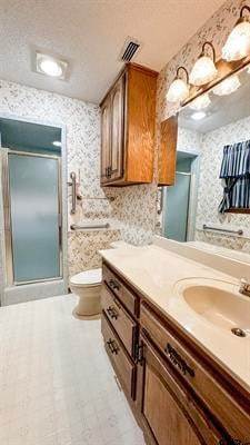 bathroom with vanity, a shower with shower door, a textured ceiling, and toilet