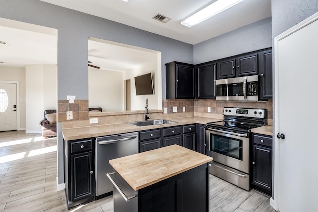 kitchen with ceiling fan, sink, tasteful backsplash, kitchen peninsula, and appliances with stainless steel finishes