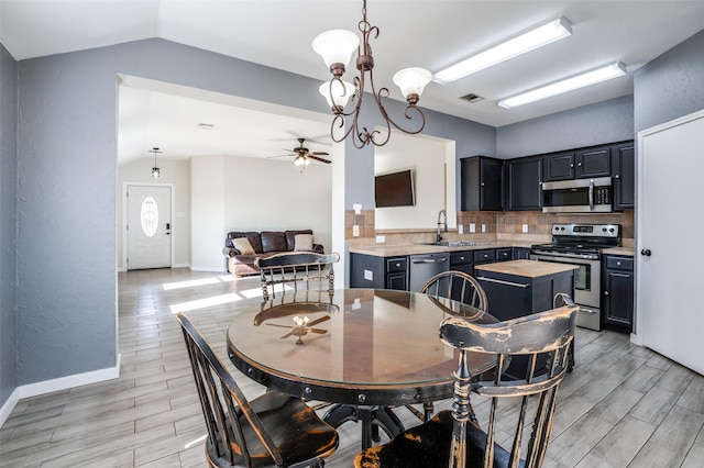 dining area featuring ceiling fan with notable chandelier, lofted ceiling, and sink