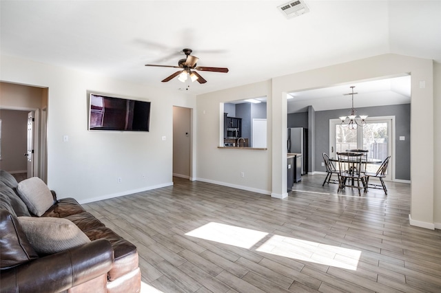 living room featuring ceiling fan with notable chandelier, light wood-type flooring, sink, and vaulted ceiling