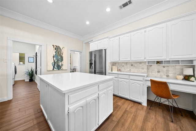 kitchen featuring stainless steel fridge with ice dispenser, backsplash, white cabinetry, and a center island