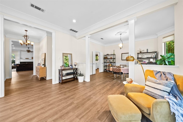 sitting room with hardwood / wood-style flooring, an inviting chandelier, decorative columns, and ornamental molding