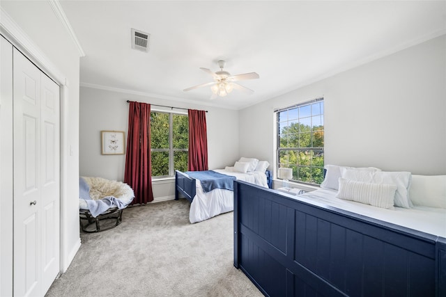 carpeted bedroom featuring a closet, crown molding, and ceiling fan