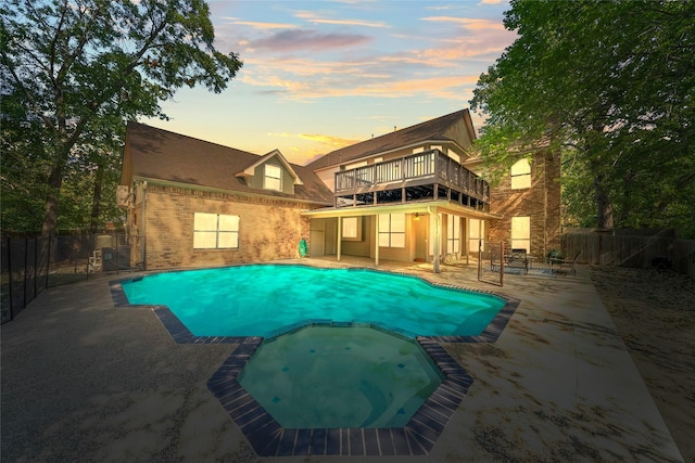 pool at dusk with an in ground hot tub and a patio