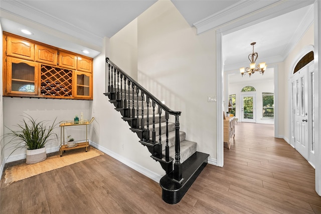 entryway featuring hardwood / wood-style floors, an inviting chandelier, and ornamental molding