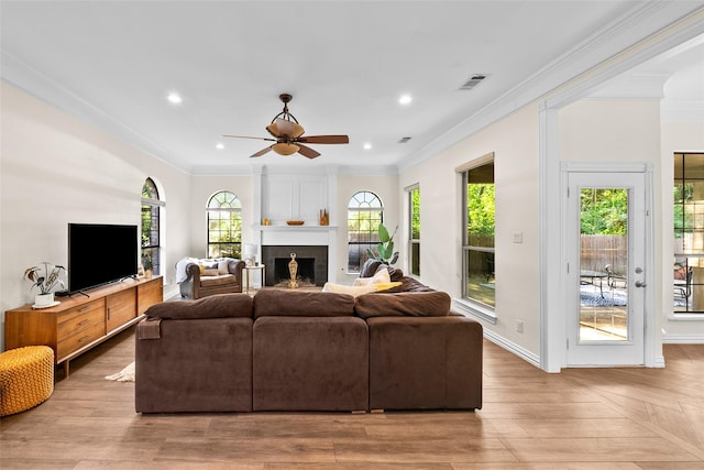 living room with ceiling fan, a large fireplace, and crown molding