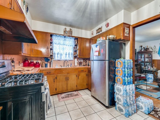 kitchen featuring tasteful backsplash, sink, light tile patterned floors, and stainless steel appliances