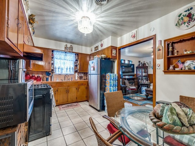 kitchen featuring stainless steel fridge, stove, sink, light tile patterned floors, and range hood