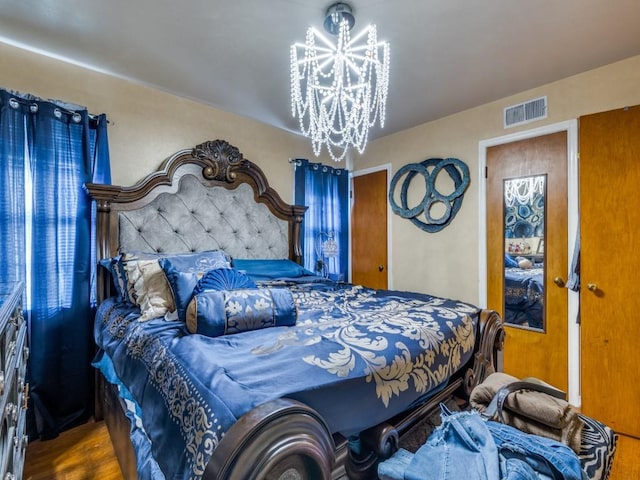 bedroom with hardwood / wood-style flooring and a notable chandelier