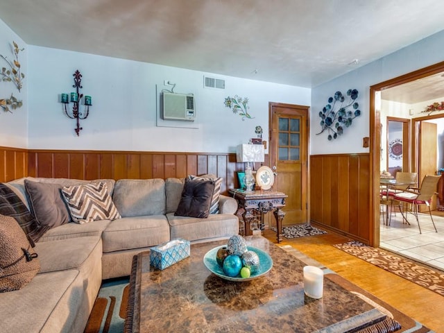 living room with a wall mounted AC, wooden walls, and hardwood / wood-style flooring