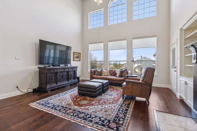 living room with baseboards, hardwood / wood-style flooring, and a towering ceiling