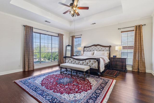 bedroom with baseboards, visible vents, a raised ceiling, and wood finished floors