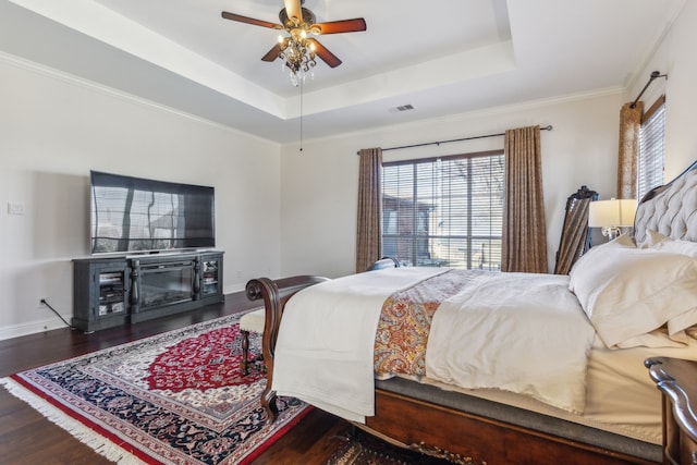bedroom featuring visible vents, multiple windows, wood finished floors, and a tray ceiling