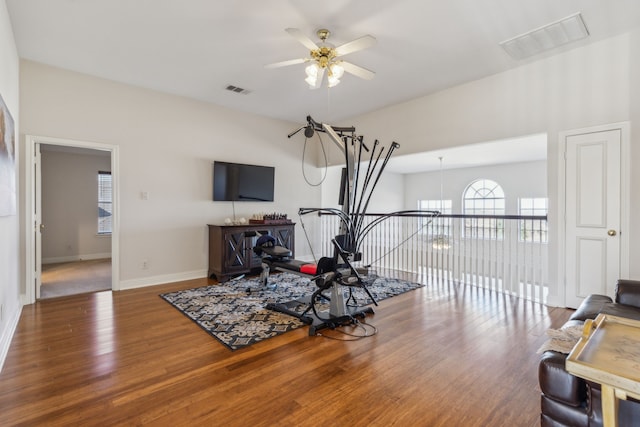 workout area with visible vents, baseboards, wood finished floors, and ceiling fan with notable chandelier