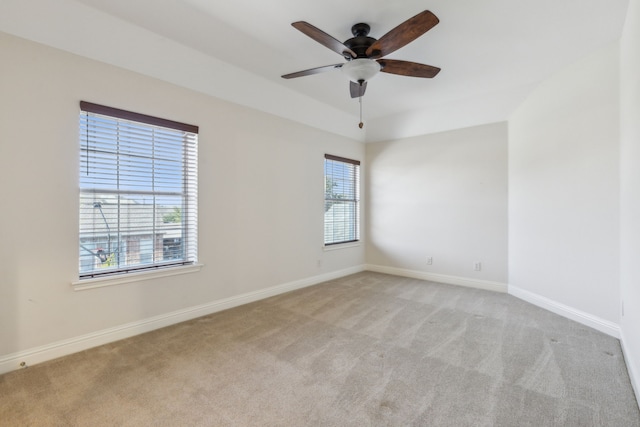 empty room with light colored carpet, a ceiling fan, and baseboards