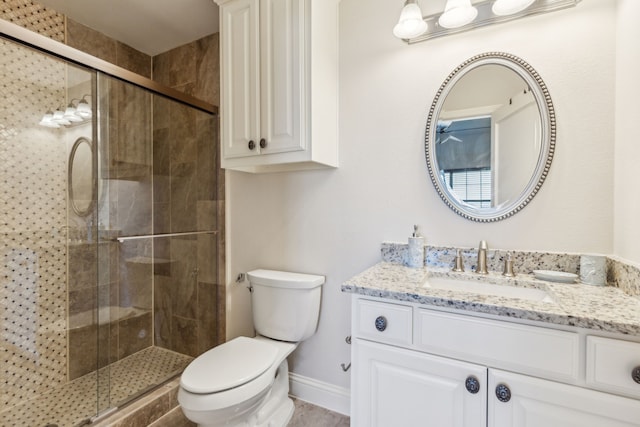 bathroom with toilet, a stall shower, vanity, and baseboards