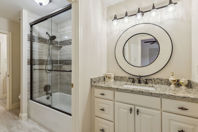 bathroom featuring baseboards, bath / shower combo with glass door, and vanity