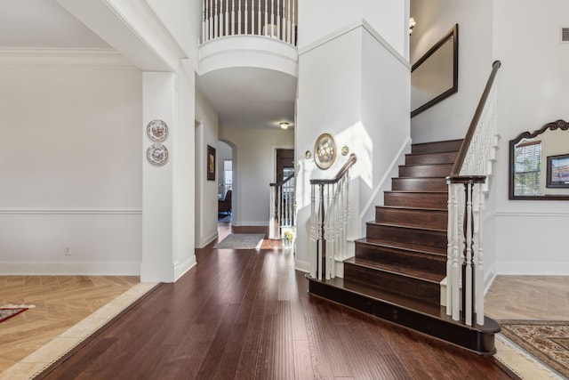 entryway featuring stairway, wood finished floors, baseboards, and arched walkways