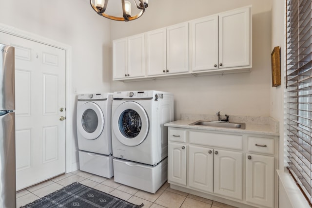 washroom with washing machine and dryer, a sink, an inviting chandelier, light tile patterned flooring, and cabinet space
