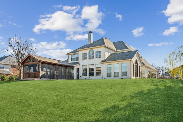 back of house with fence, a chimney, stucco siding, a lawn, and a sunroom