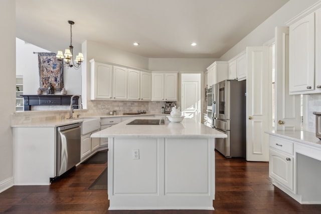 kitchen with decorative backsplash, a chandelier, appliances with stainless steel finishes, white cabinetry, and a center island