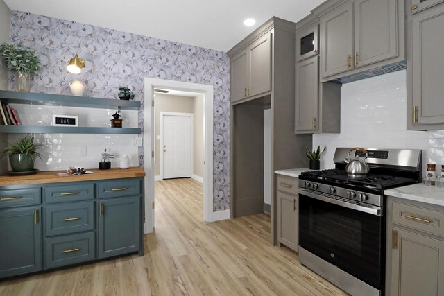 kitchen with wood counters, stainless steel range with gas cooktop, light hardwood / wood-style floors, and backsplash