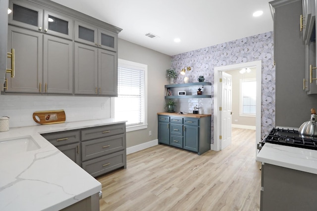 kitchen featuring light stone countertops, a wealth of natural light, light wood-type flooring, and stove