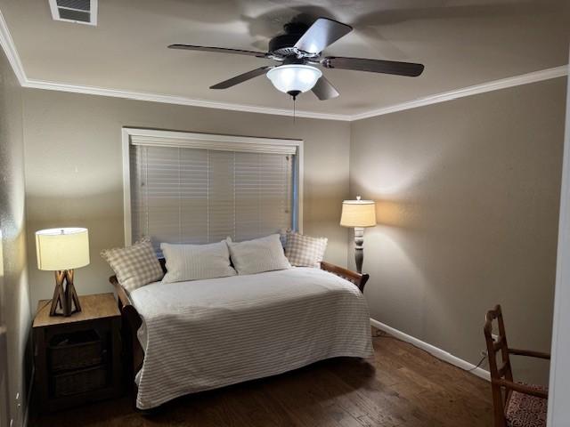 bedroom featuring dark hardwood / wood-style flooring, ceiling fan, and crown molding