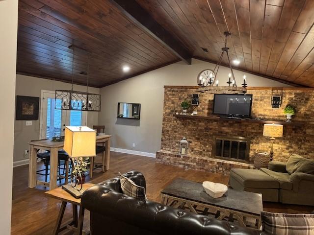 living room with lofted ceiling with beams, hardwood / wood-style flooring, a fireplace, a notable chandelier, and wood ceiling