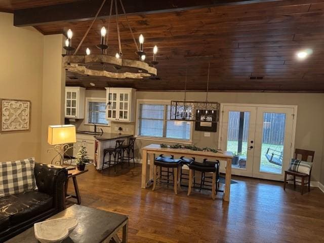 dining room featuring beam ceiling, dark hardwood / wood-style flooring, wooden ceiling, and french doors