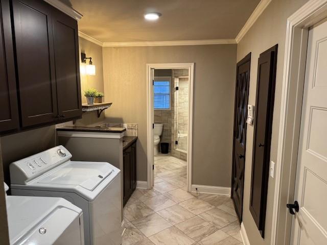 clothes washing area with washing machine and dryer, cabinets, and ornamental molding