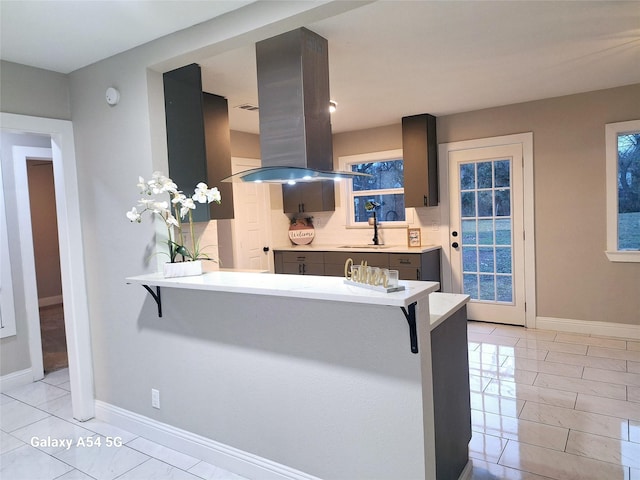 kitchen featuring a breakfast bar area, island exhaust hood, kitchen peninsula, and tasteful backsplash